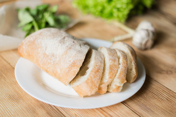 Sliced bread, ciabatta on a white plate. Preparation for the preparation of bruschetta.