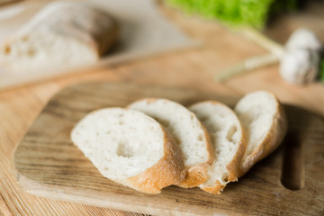 Sliced bread, ciabatta on wooden background. Preparation for the preparation of bruschetta.