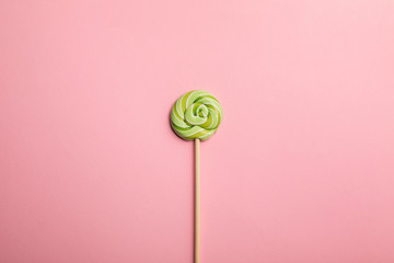 top view of delicious green swirl lollipop on wooden stick on pink background
