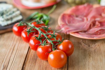 A branch of fresh cherry tomatoes on a wooden background.