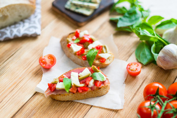 Traditional Italian bruschetta with blue cheese, feta, tomatoes, basil leaves, jamon on a wooden background.
