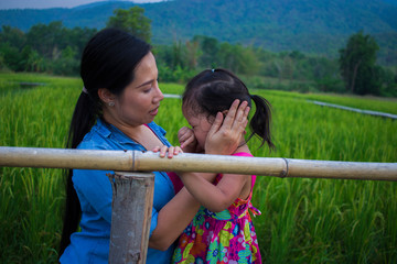 Young mother hugging and soothing a crying little daughter, Asian mother trying to comfort and calm down her crying child