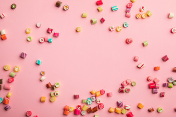 top view of delicious multicolored candies scattered on pink background with copy space