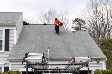 House during day over garage with truck, gray color Single Family Home and man walking on roof shingles and ladder during repair © Andriy Blokhin