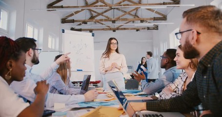 Young experienced millennial business woman speaking before creative team of office workers, training workplace seminar.