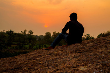 With deep thought, the boy looked at the sunset from hill