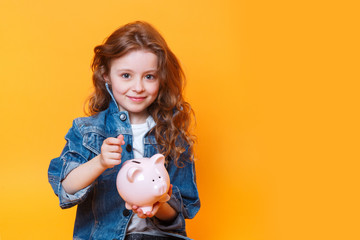 Fototapeta na wymiar Responsible girl putting money into piggy bank for future saving