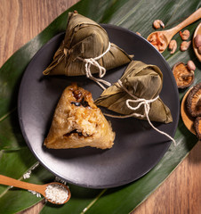 Zongzi, steamed rice dumplings on wooden table bamboo leaves, food in dragon boat festival duanwu concept, close up, copy space, top view, flat lay