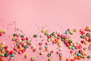 Fototapeta na wymiar top view of colorful tasty candies and sprinkles scattered on pink background with copy space
