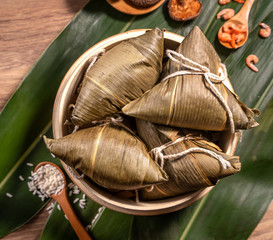 Zongzi, steamed rice dumplings on wooden table bamboo leaves, food in dragon boat festival duanwu concept, close up, copy space, top view, flat lay