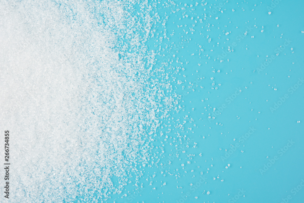 Wall mural white sugar splash on blue background texture top view