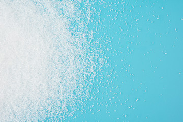 White sugar splash on blue background texture top view