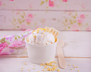 Vanilla ice cream with white chocolate on the white table and floral background.