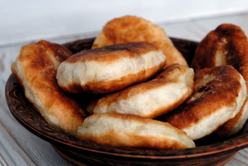 Potato pies on a ceramic dish opposite light background. Shallow depth of field