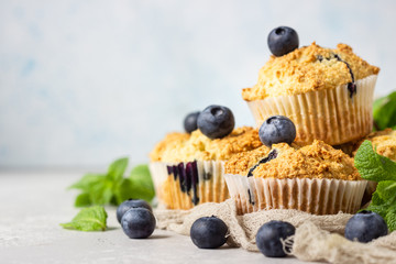 Blueberry muffins with fresh berries and mint leaves on light grey stone background. Copy space.