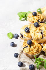 Blueberry muffins with fresh berries and mint leaves on light grey stone background. Copy space.