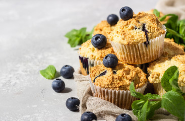Blueberry muffins with fresh berries and mint leaves on light grey stone background. Copy space.
