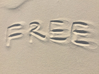 The word Free written in the sand on the beach.