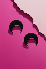 Shot of massive earrings in view of an upside down half moon. The ink black set is isolated...