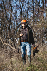 Naklejka premium Elderly hunter with wild bird in orange hat