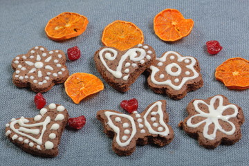 Obraz na płótnie Canvas Gingerbread cookies decorated with a pattern of white glaze. On a background of gray fabric. Decorated with decorative elements of dried fruit