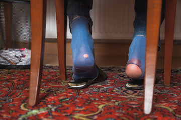 Man sits on chair on his socks can see holes
