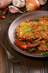 Homemade tasty potato pancakes in clay dish with sun-dried tomatoes