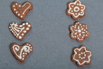 Gingerbread cookies decorated with a pattern of white glaze. On a background of gray fabric.