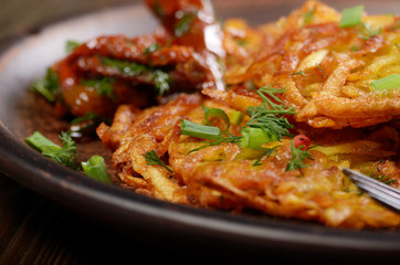 Closeup view at Homemade tasty potato pancakes in clay dish with sun-dried tomatoes