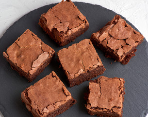 pieces of chocolate brownie on a black round graphite plate