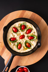 Food concept rising dough for Homemade organic Focaccia in skillet iron pan on black background with copy space