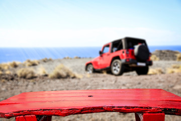 Red old wooden table. A summer car on the cliffs of Gran Canaria island. A place for your products. Summer time and ocean landscape © magdal3na