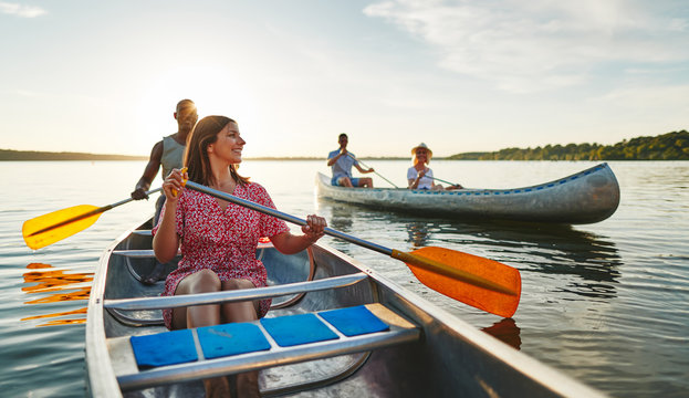 Young woman smiling while canoeing with friends in the summer