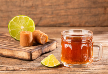 Fresh homemade Aguapanela, Agua de Panela or Aguadulce, a popular Latin American sweet drink made of panela unrefined whole cane sugar boiled in water, served warm or cold with lime.
