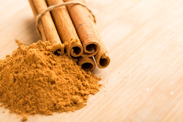 Cinnamon sticks and powder on wooden table