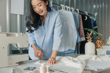 Obraz premium Young female fashion designer working on her designs in the studio. Fashion designer drawing sketches for new collection. Beautiful fashion woman designer drawing in studio .