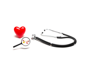Front view of plastic red heart model, stethoscopes, and drugs with magnifying glass on white background