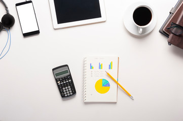 Top view of tablet, smartphone, calculator, notebook and a cup of coffee on white background