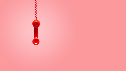Red old telephone receiver hanging on pink background