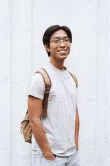 Smiling young asian man student carrying backpack