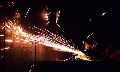 Metal grinding on steel pipe with flash of sparks close up