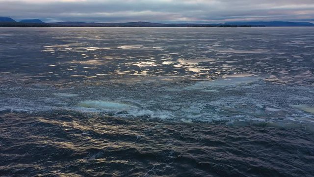 Nature- Soft waves on the Moosehead lake. Completely frozen lake on the other side with a glare on the floe.