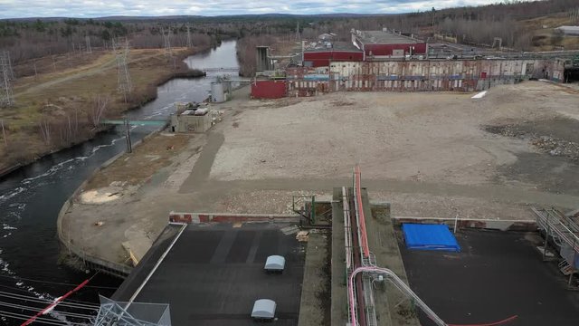 Environmentally damaging industrial buildings contaminating a local river and emmitting toxic chemicals. 
Muted, desaturated style, 4k footage.