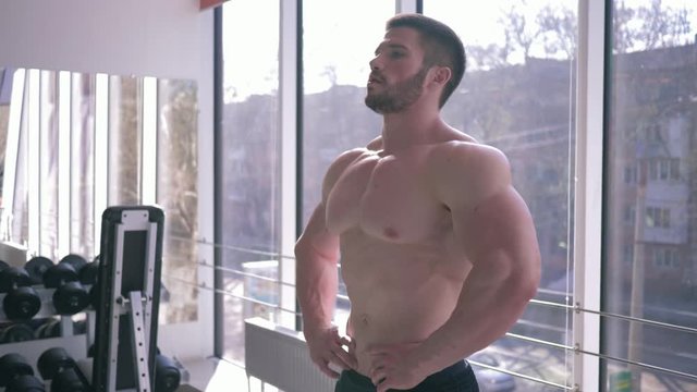 beautiful muscular sport male bare-chested with athletic body does warm-up after strength training in building muscle in gym