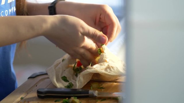 Cooking a vegetarian meal at home fulling a pita bread with many vegetables.