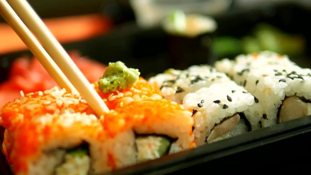 close-up. someone takes sushi with chopsticks, rolls.