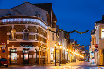 Fototapeta na wymiar Parnu, Estonia. Night View Of Famous Ruutli Street With Old Buildings, Restaurants, Cafe, Hotels And Shops In Festive Evening Night Christmas Xmas New Year Illuminations
