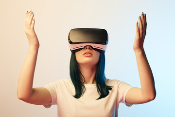 attractive young woman gesturing while wearing virtual reality headset on beige and blue
