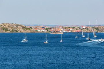 Sailboats at sea with a coastal village in the Swedish coastline