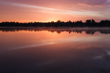 Fototapeta premium Sunrise over the forest lake. Reflection of the sky in the lake. Summer